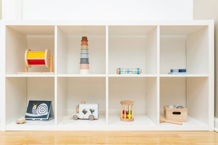 A tidy white shelf with simple wooden toys