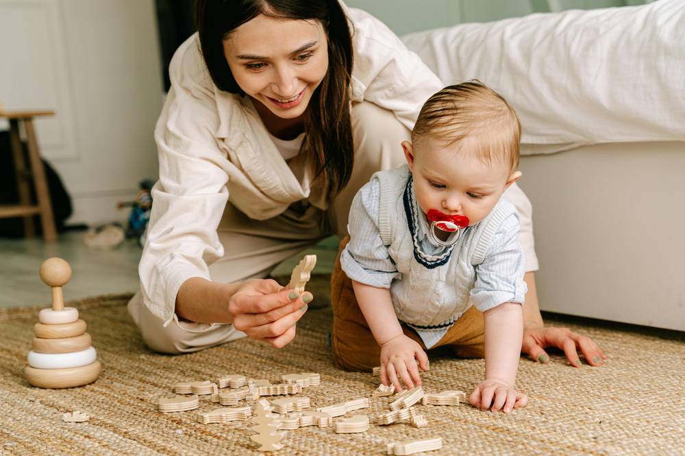 A caregiver and baby playing with wooden toys together